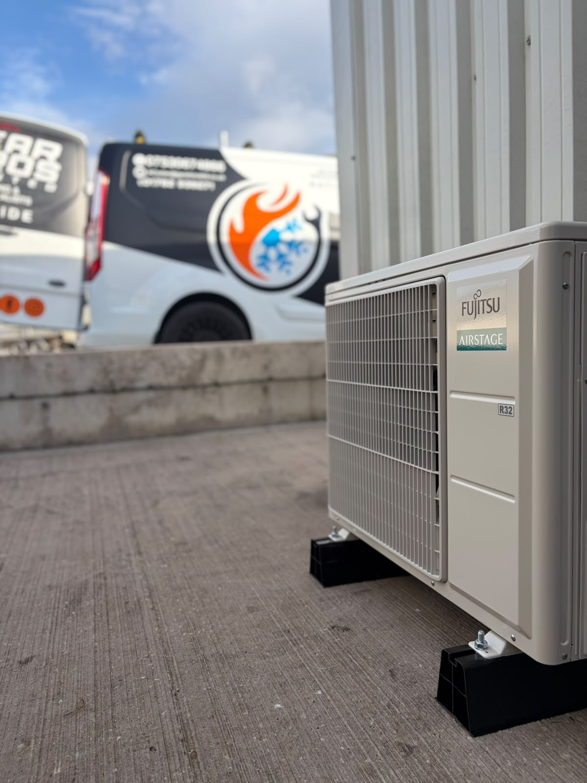 Newly installed Fujitsu Airstage outdoor air conditioning unit on site with Gear Bros Ltd vans behind